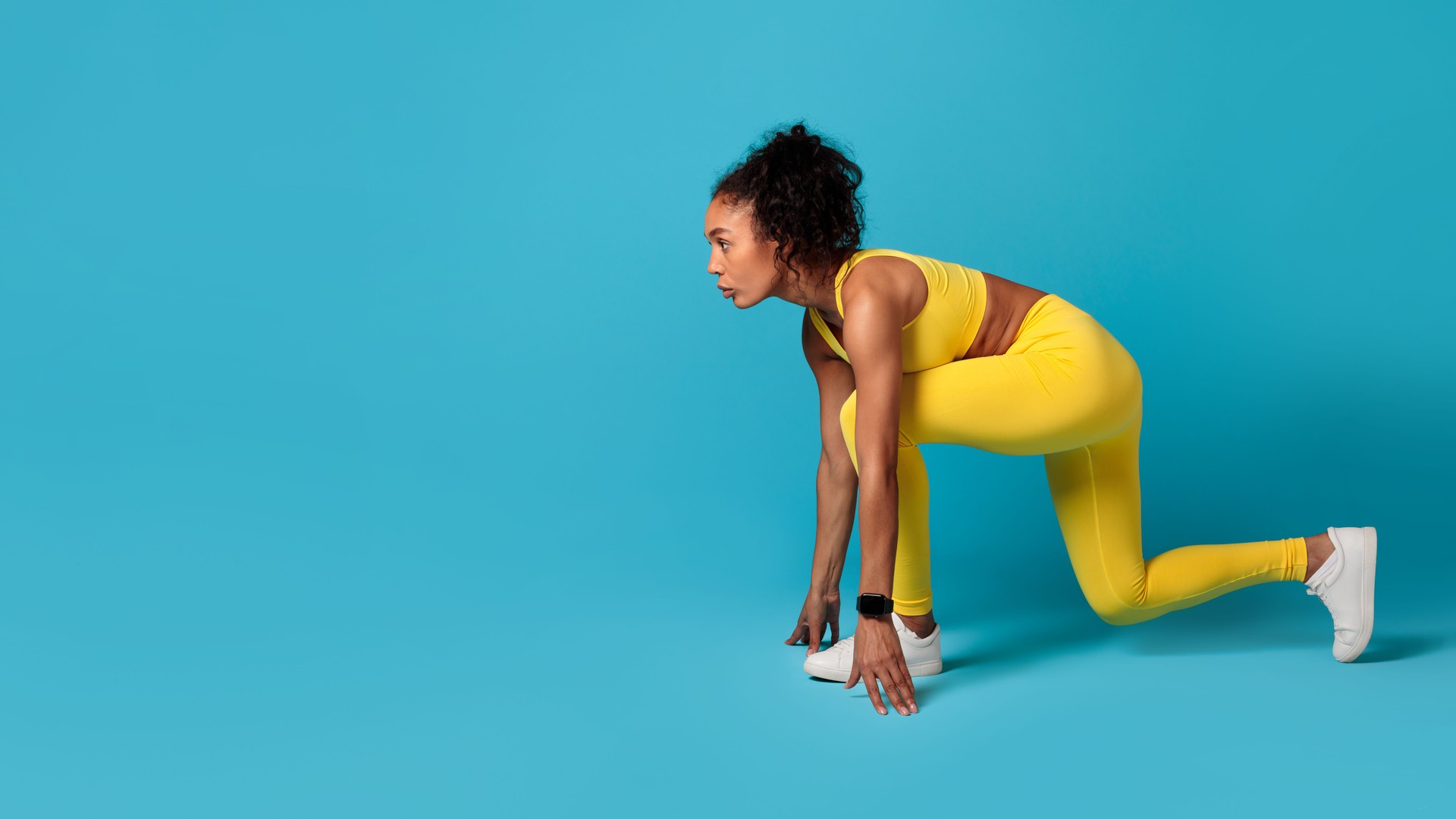 black woman confidently posing in crouch position on blue background